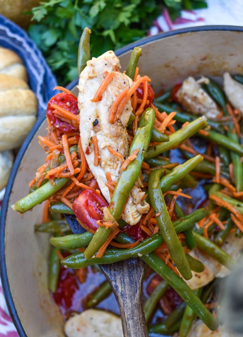 a wooden spatula holding up a scoop of balsamic chicken and vegetables