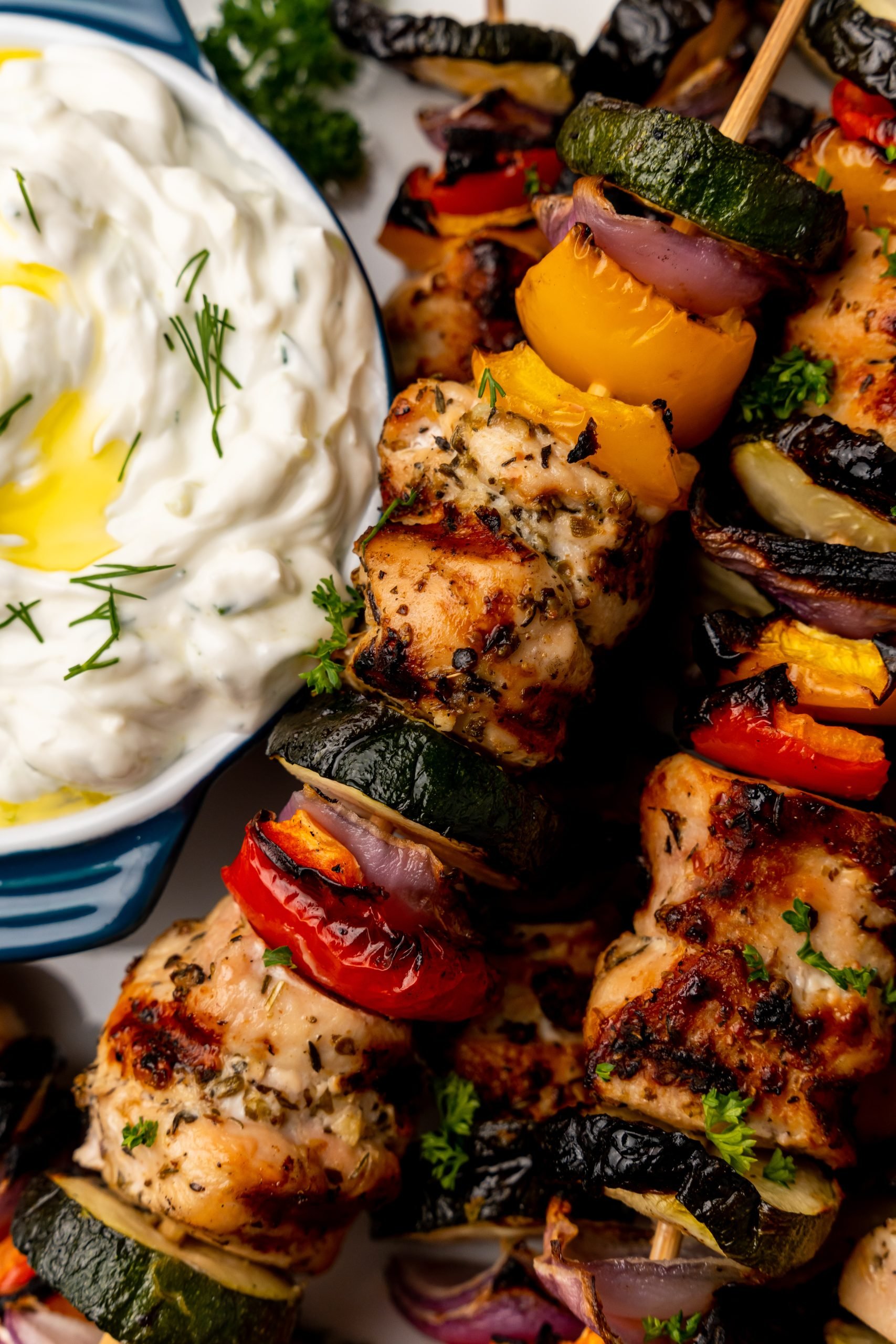 grilled chicken kabobs next to a bowl of homemade tzatziki sauce