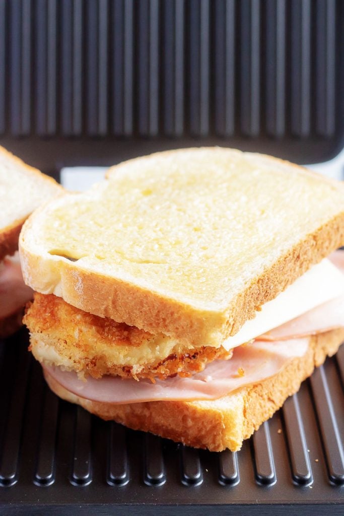 Chicken Cordon Bleu Panini sandwich sitting on a panini press ready to be grilled