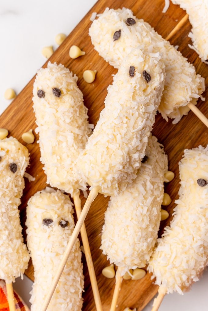 Halloween banana ghost pops on a wooden cutting board 