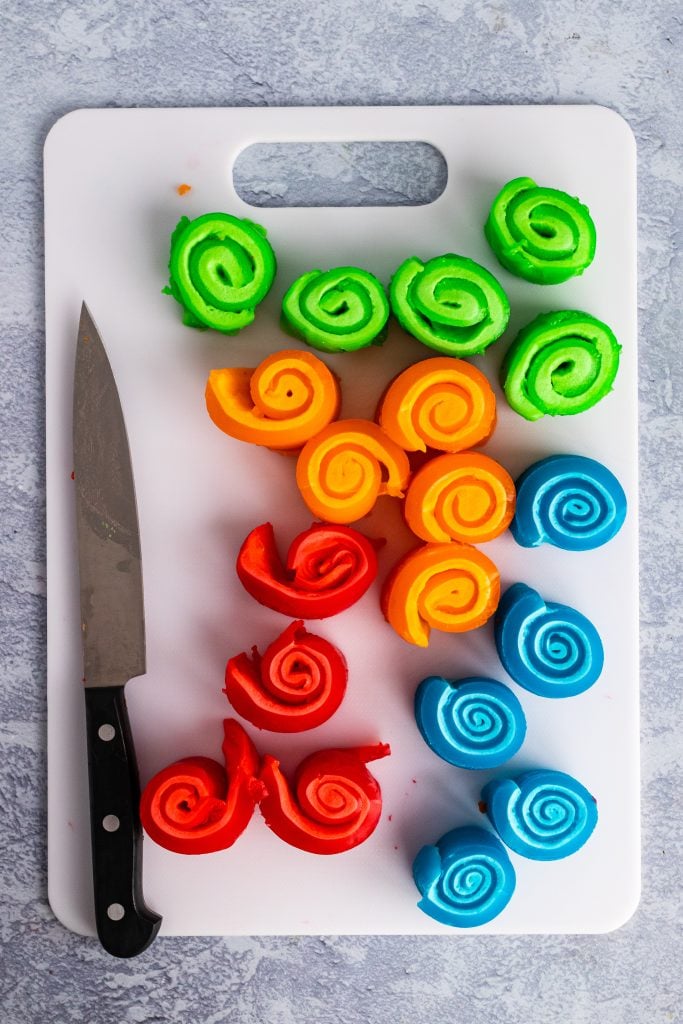 marshmallow pinwheels sliced and arranged in rows on a white plastic cutting board