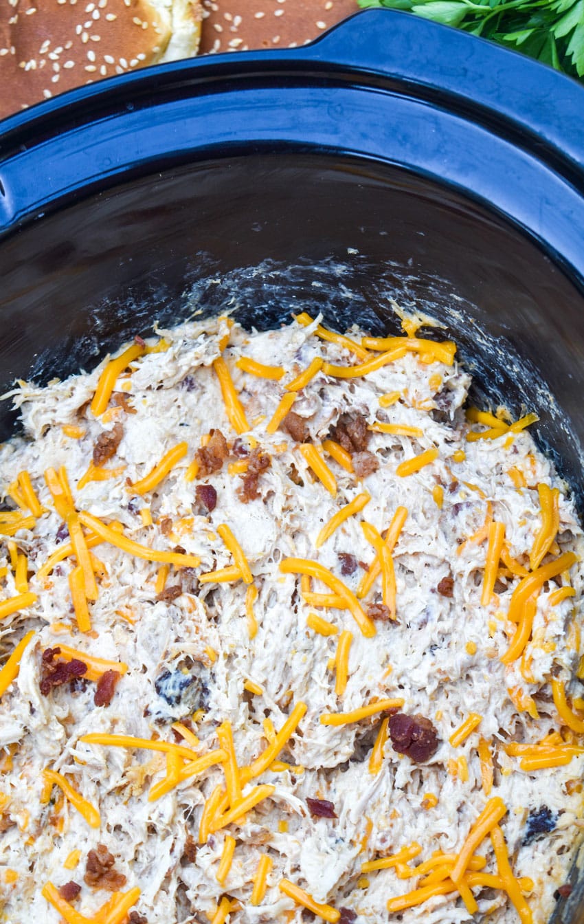 crack chicken in the black bowl of a slow cooker