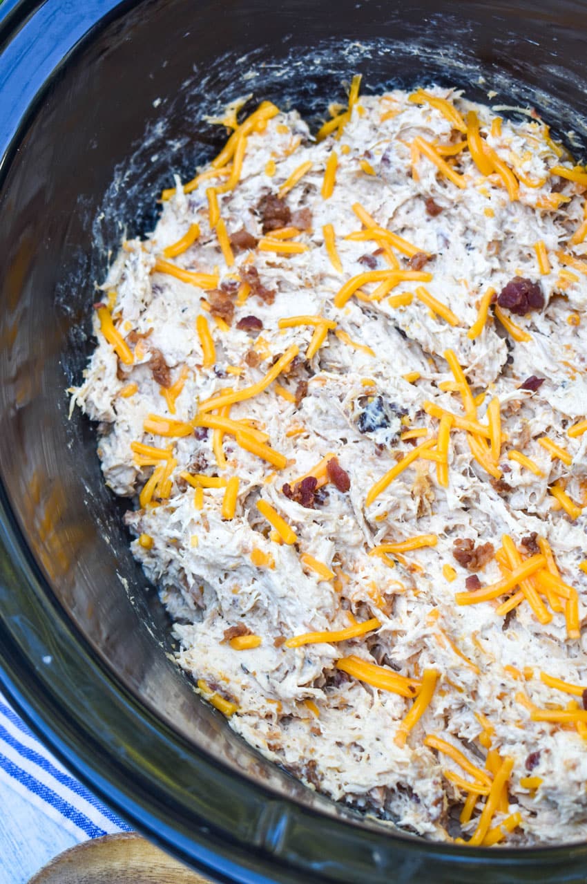 crack chicken in the black bowl of a slow cooker