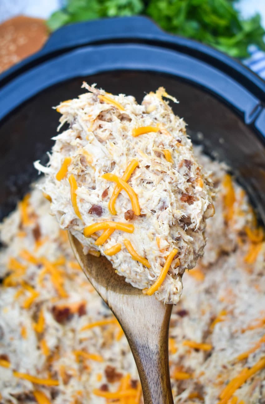 a wooden spoon holding up a scoop of crockpot crack chicken