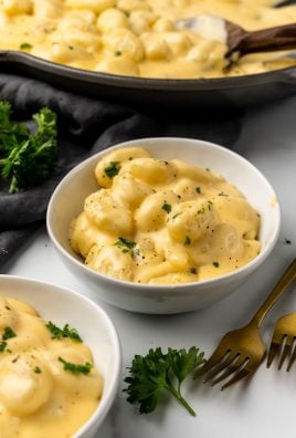 three cheese gnocchi mac and cheese in a white bowls next to a black skillet