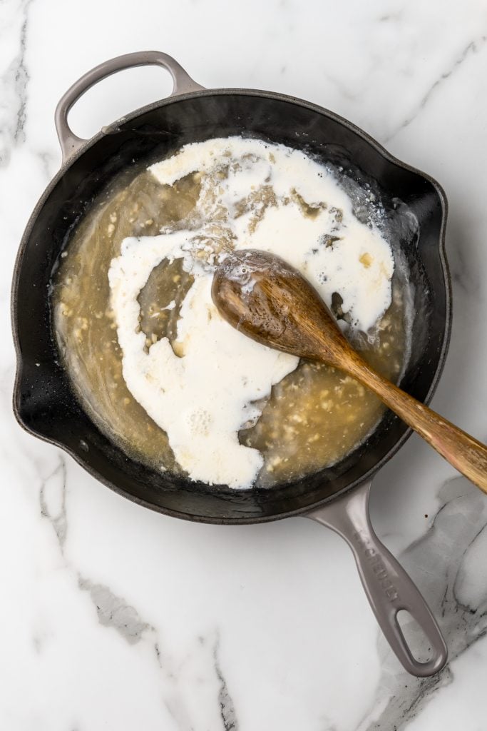 a roux being mixed up with a wooden spoon in a cast iron skillet