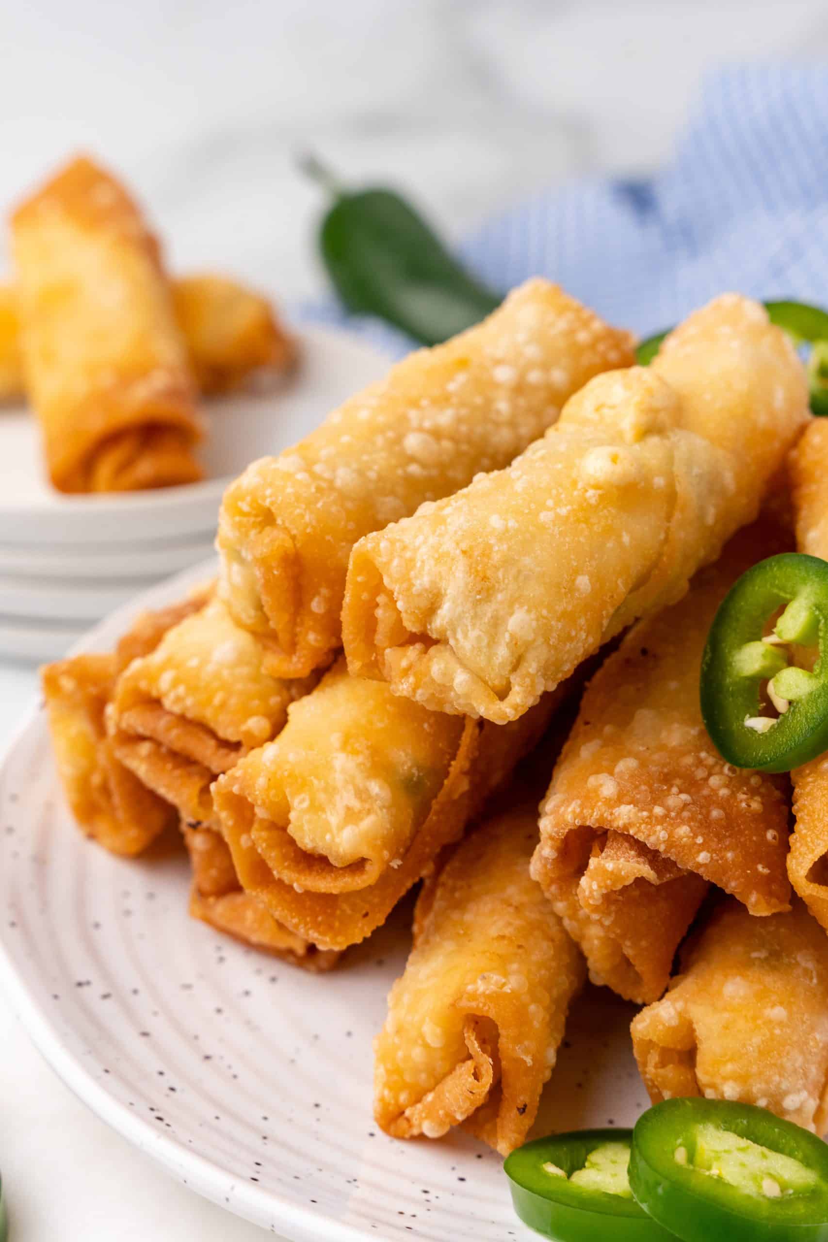 jalapeno popper egg rolls stacked on small white plates