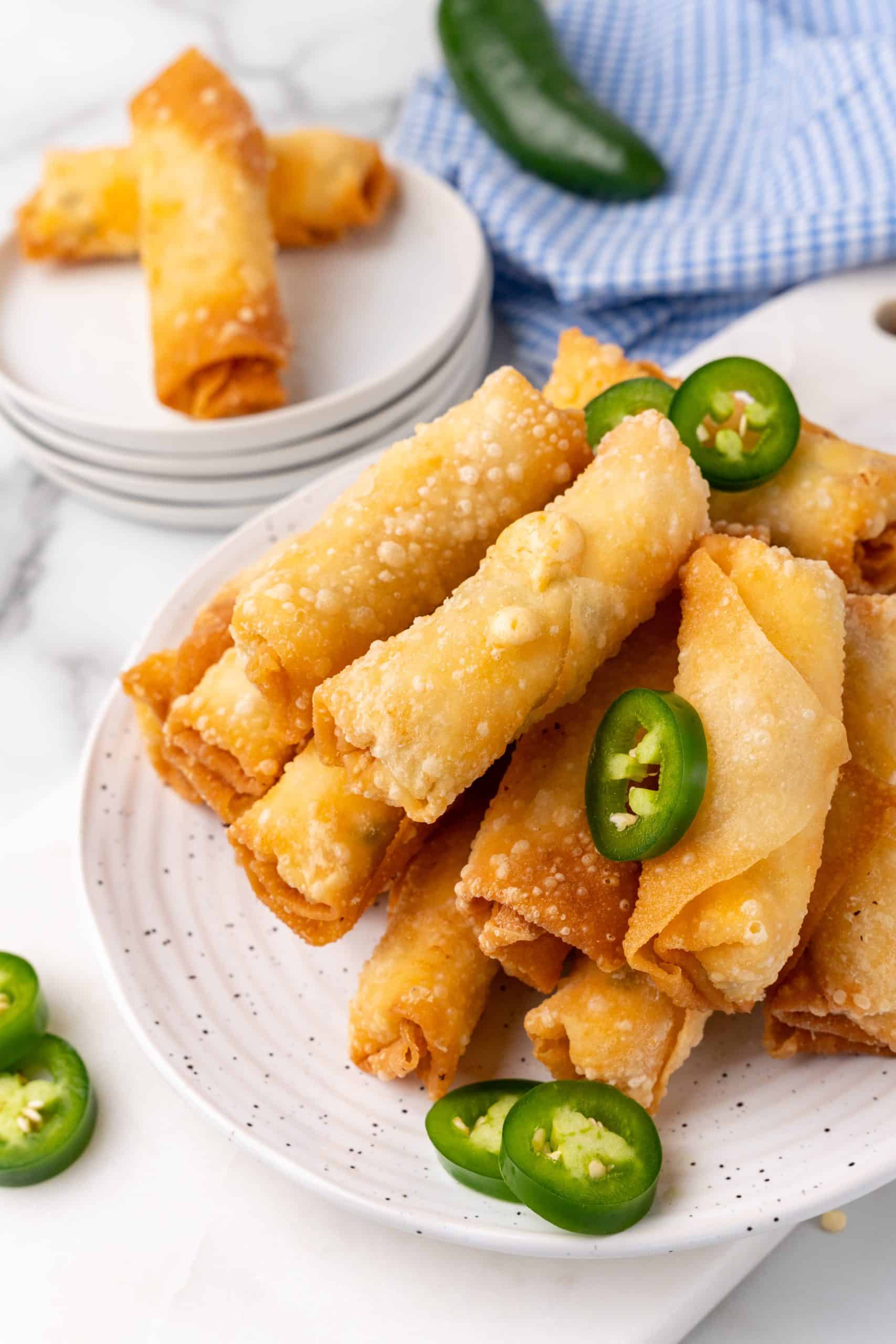 jalapeno popper egg rolls stacked on small white plates