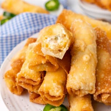 jalapeno popper egg rolls stacked on small white plates