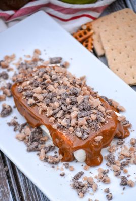 a brick of cream cheese topped with thick caramel sauce and topped with crushed toffee candy pieces