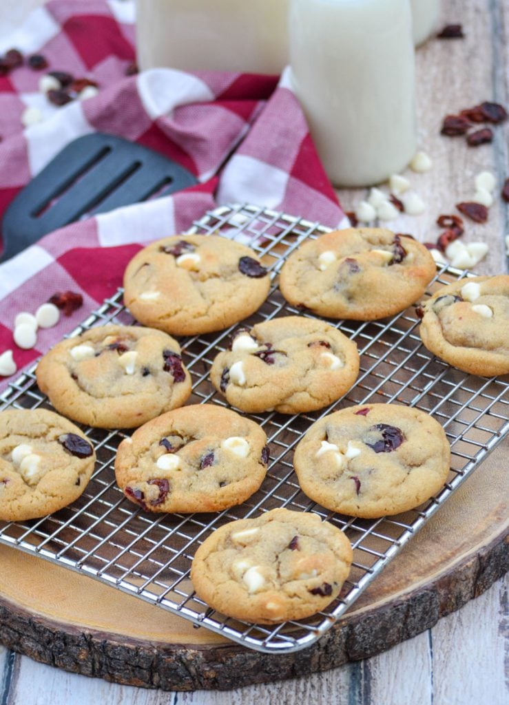 cranberry white chocolate chip cookies shown on a wire rack on top of a red and white plaid cloth napkin