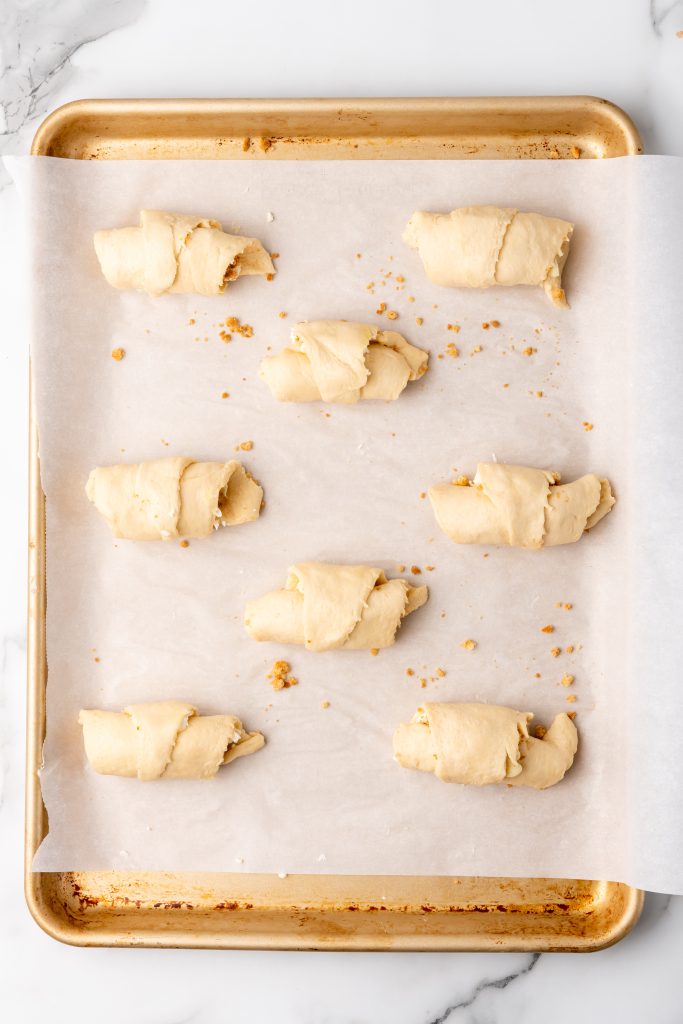 cream cheese stuffed crescent rolls on a parchment paper lined baking sheet