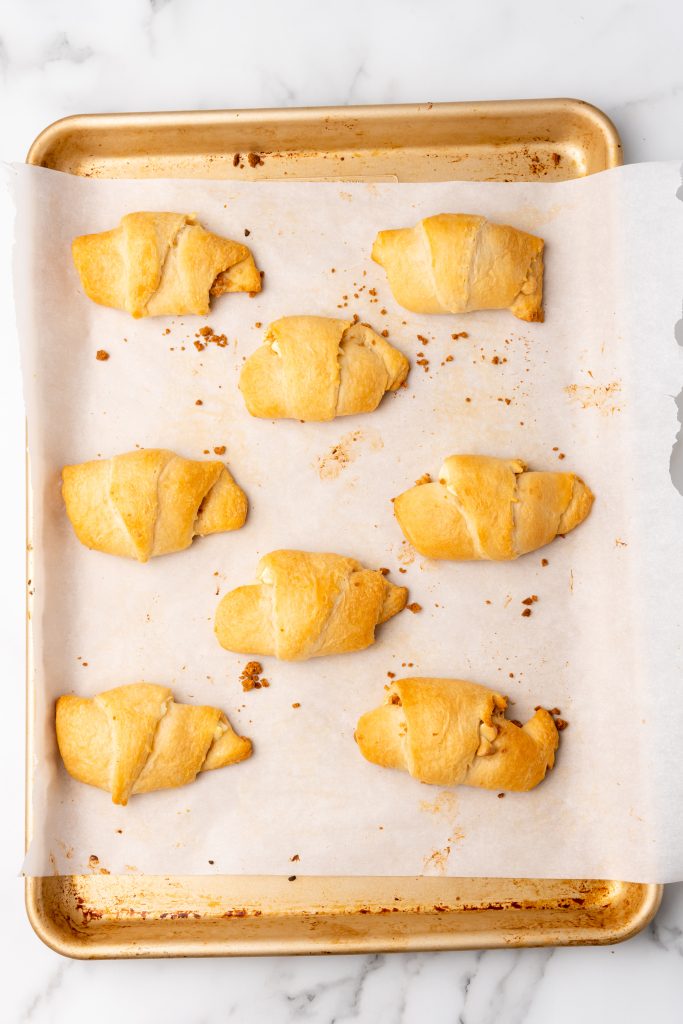 baked gingerbread stuffed crescent rolls on a parchment paper lined baking sheet