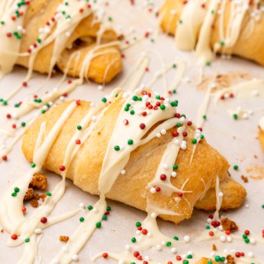 sprinkle topped white chocolate gingerbread crescent rolls on a piece of parchment paper