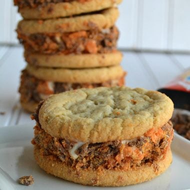 butterfinger cruster sugar cookie ice cream sandwiches are stacked three high with one in front of the stack shown on a small white plate
