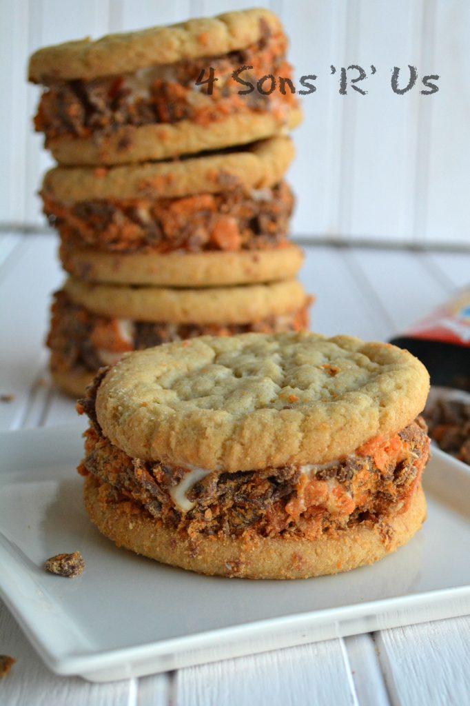 Butterfinger Sugar Cookie Ice Cream Sandwiches stacked three high with a fourth shown in the front on top of a small white plate