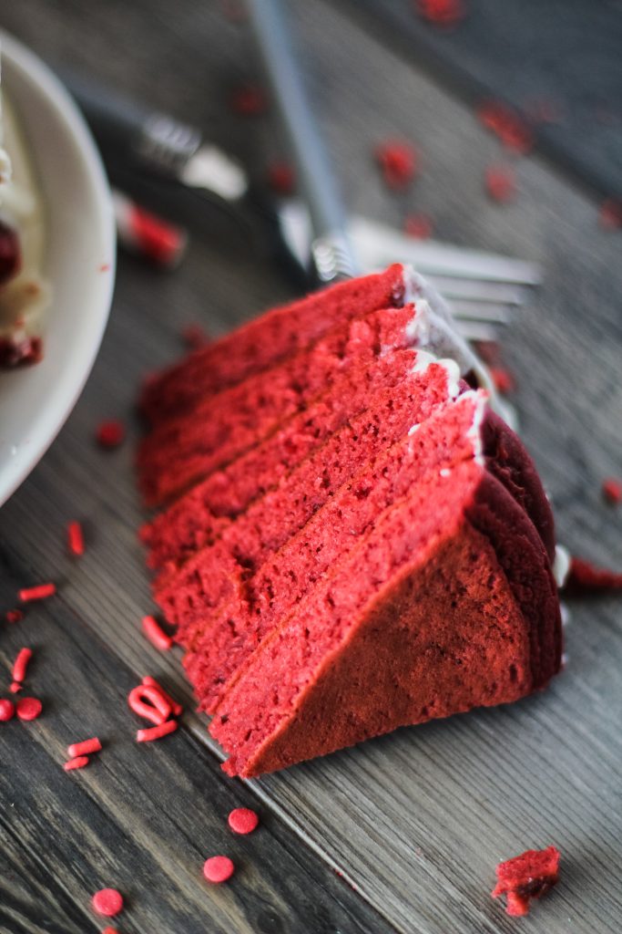 a forkful of red velvet pancakes with cream cheese glaze removed and shown on a wooden background