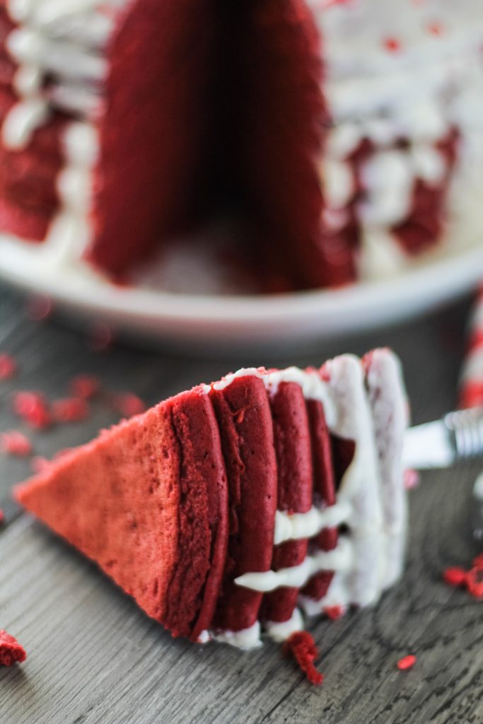 a forkful of red velvet pancakes with cream cheese glaze removed and shown on a wooden background