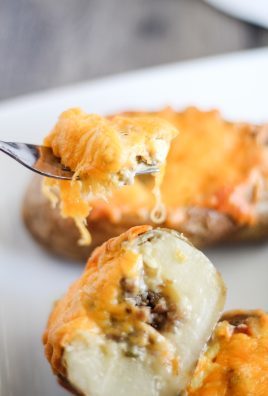a fork shown lifting a cheesy bite out of a twice baked potato