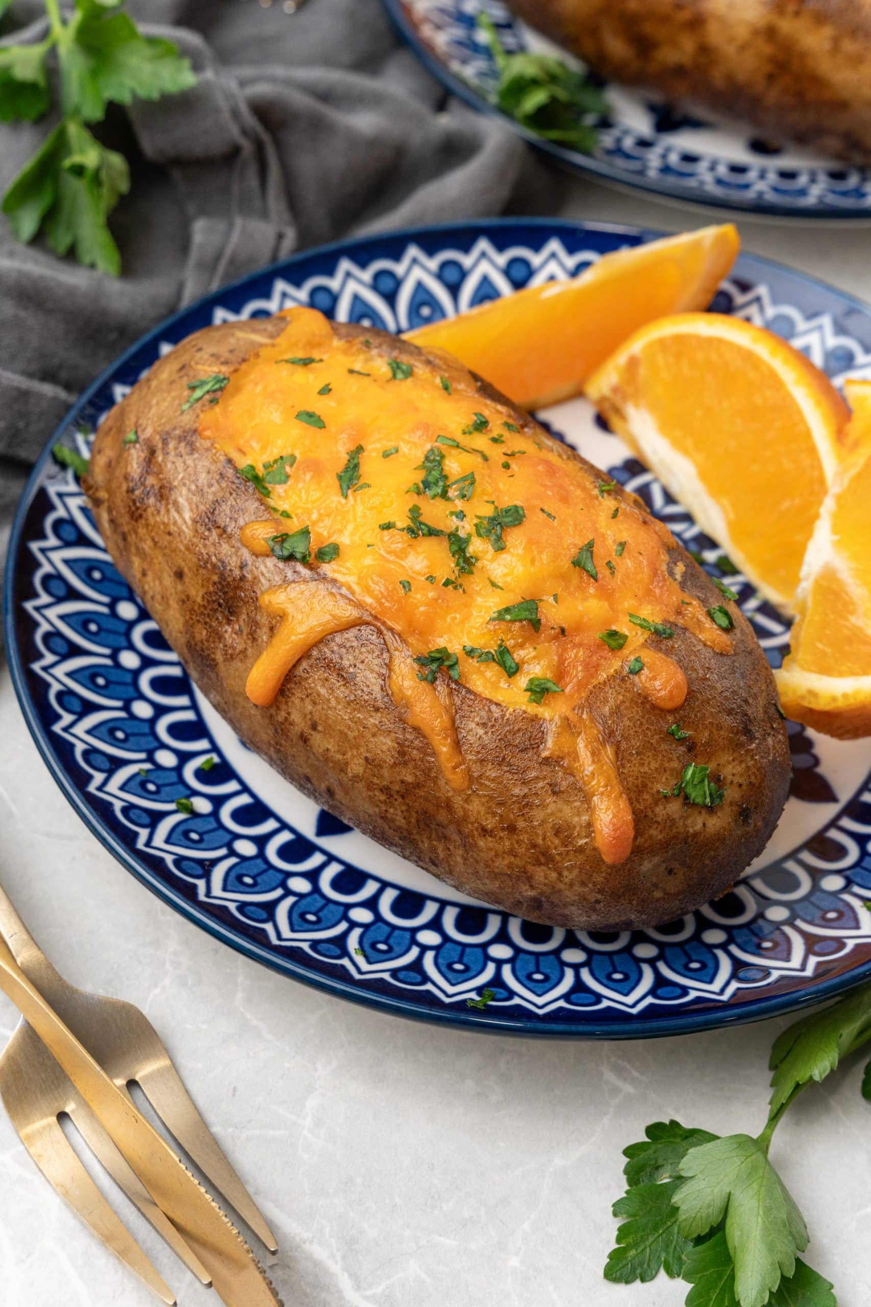 a twice baked breakfast potatoes on a blue and white plate with orange slices on the side