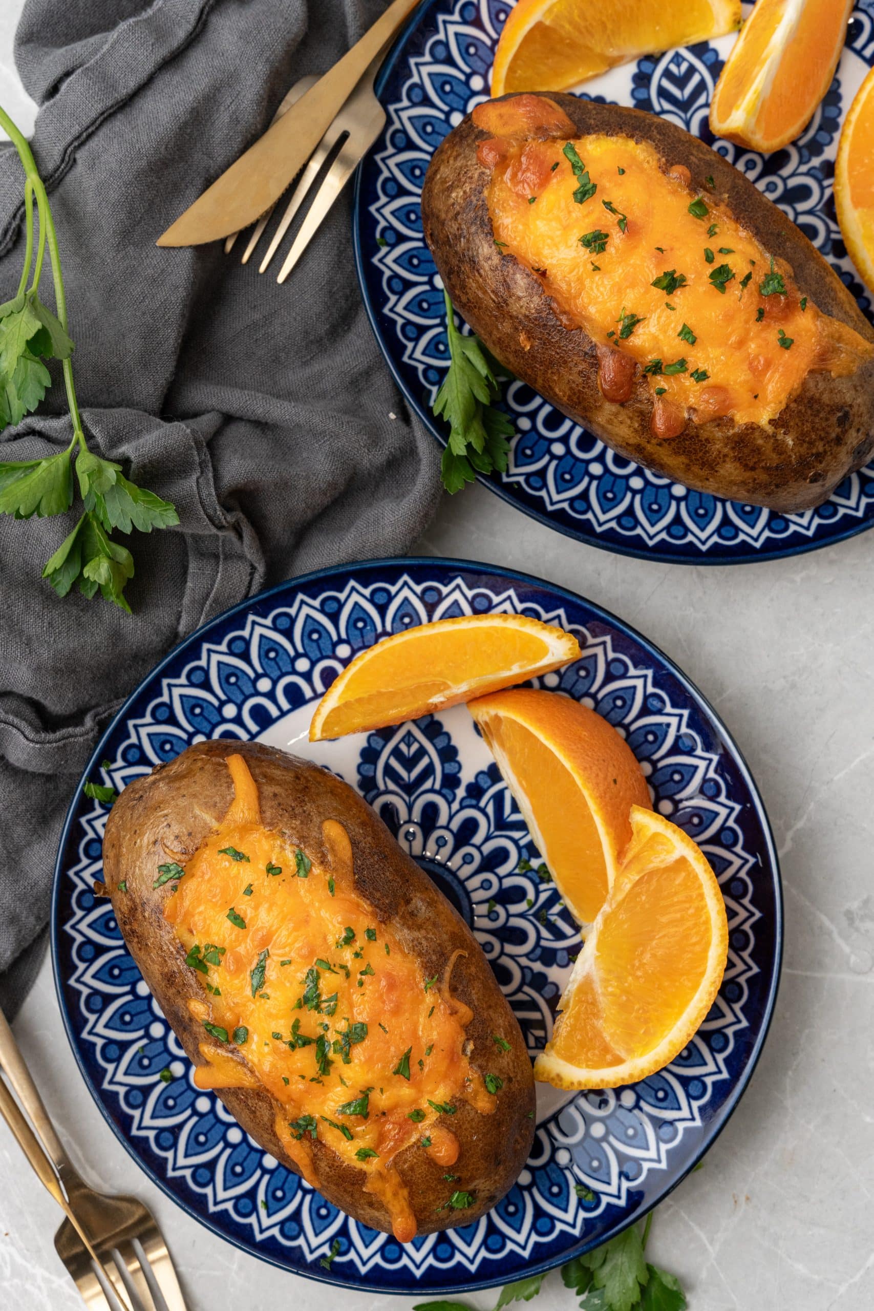 twice baked breakfast potatoes on blue and white plates with orange slices on the side