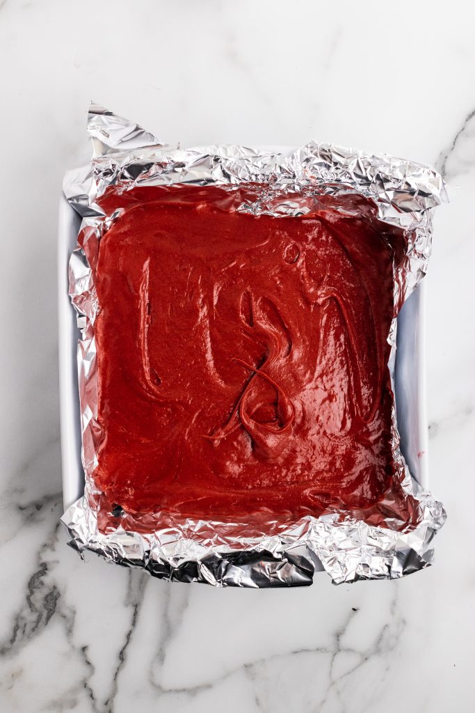 red velvet brownie batter in a foil lined baking dish