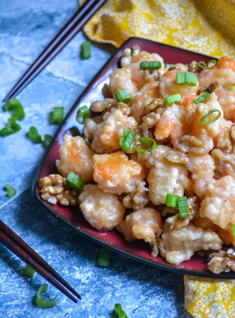 crispy honey walnut shrimp piled on a red and black square plate