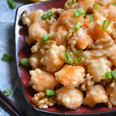 crispy honey walnut shrimp piled on a red and black square plate