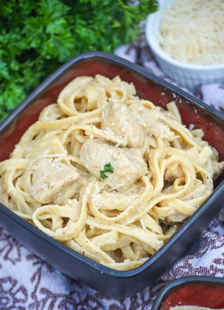 cajun chicken alfredo pasta shown in a black bowl topped with freshly chopped parsley and shredded Parmesan cheese