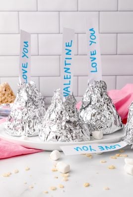 aluminum foil wrapped Hershey's kiss rice krispie treats on a white plate