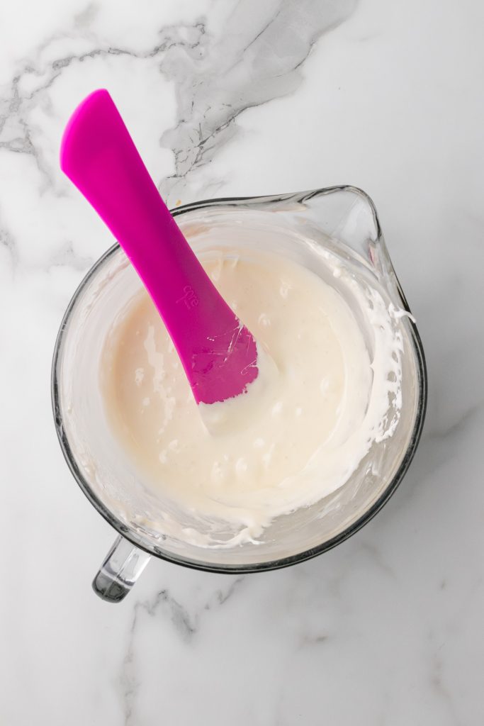 melted marshmallows in a glass measuring jar with a pink silicone spatula