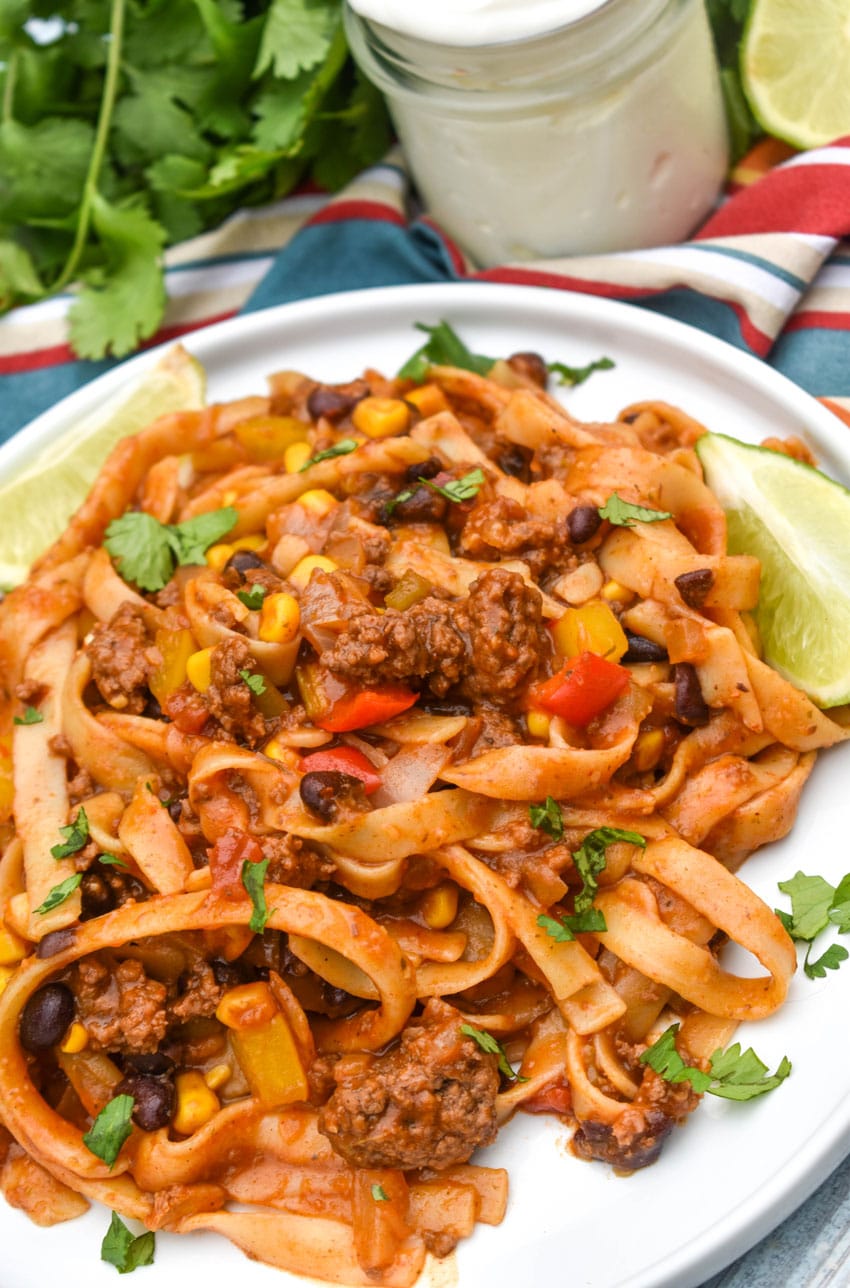 one pot taco spaghetti topped with fresh cilantro leaves on a white plate