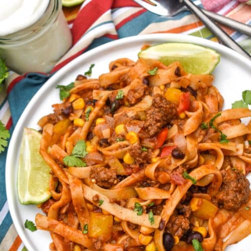 one pot taco spaghetti topped with fresh cilantro leaves on a white plate