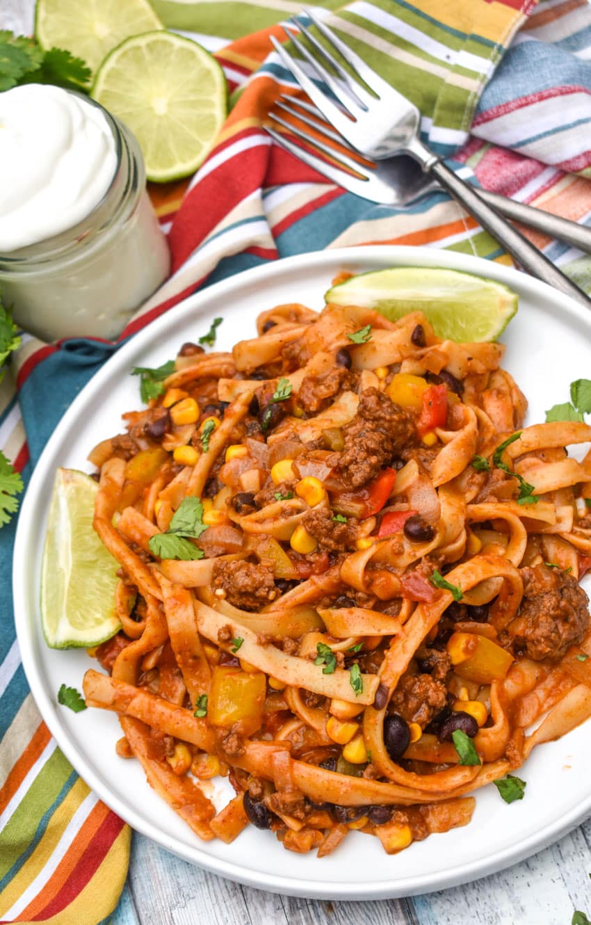 one pot taco spaghetti topped with fresh cilantro leaves on a white plate