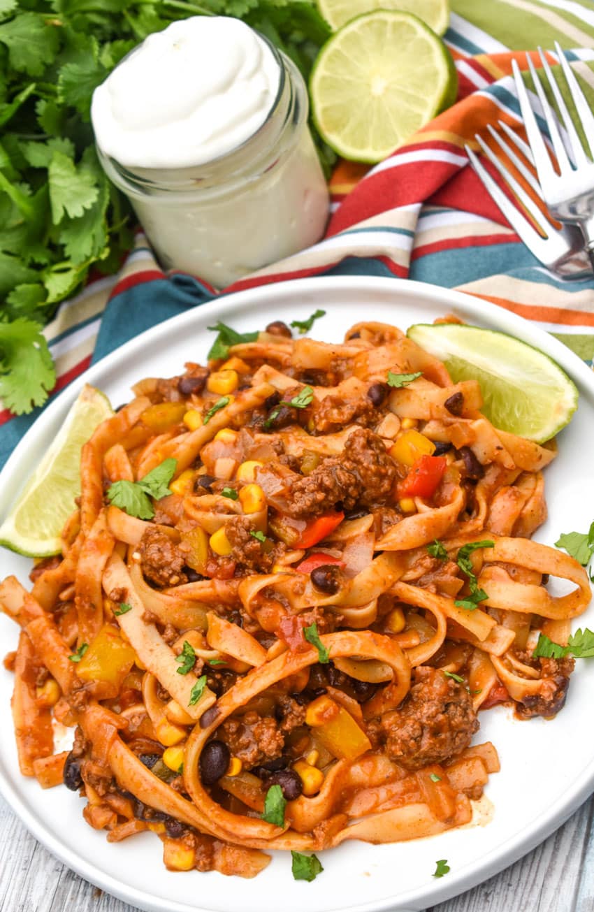 one pot taco spaghetti topped with fresh cilantro leaves on a white plate