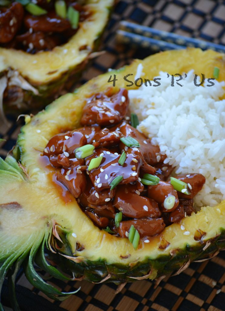 Chicken Teriyaki Pineapple Boats shows saucey, teriyaki glazed chicken pieces served next to tender white rice in a halved, hollowed out pineapple bowl