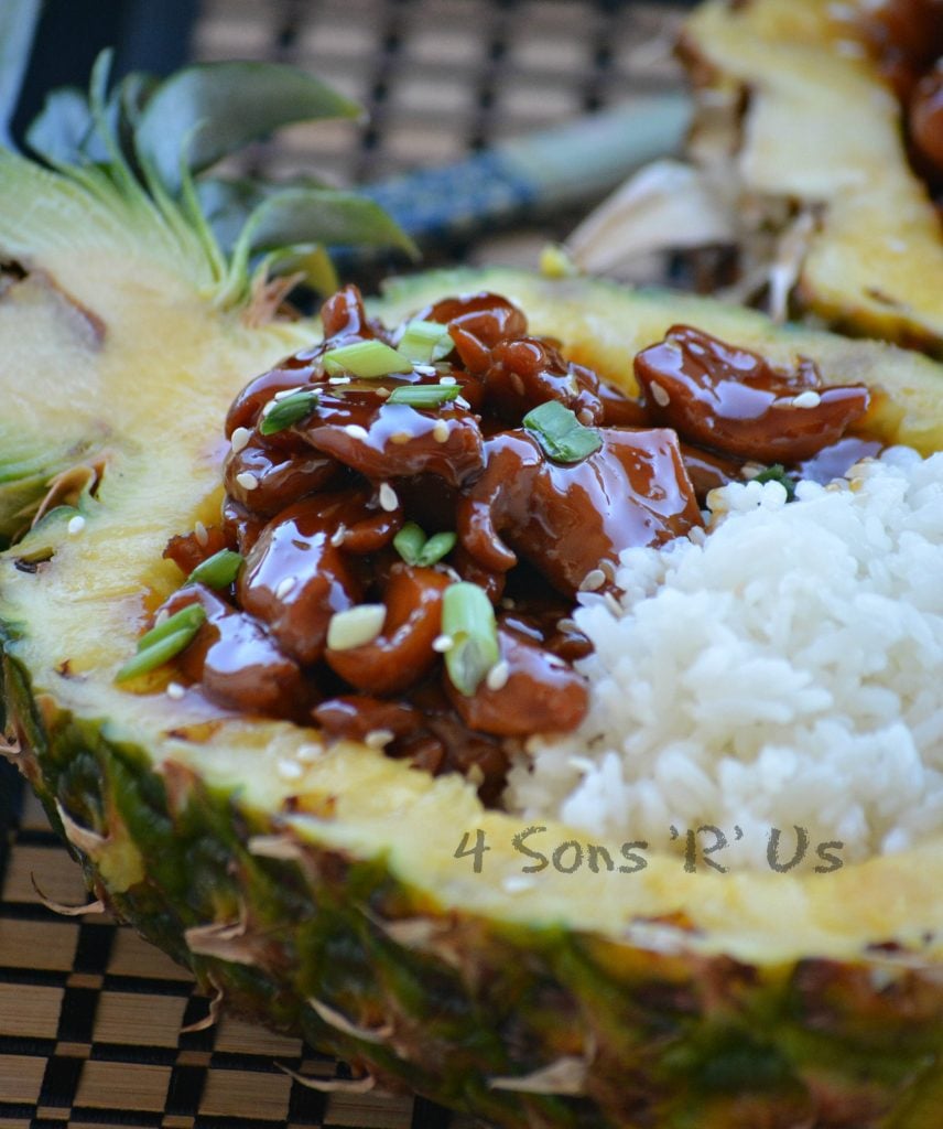 Chicken Teriyaki Pineapple Boats shows saucey, teriyaki glazed chicken pieces served next to tender white rice in a halved, hollowed out pineapple bowl