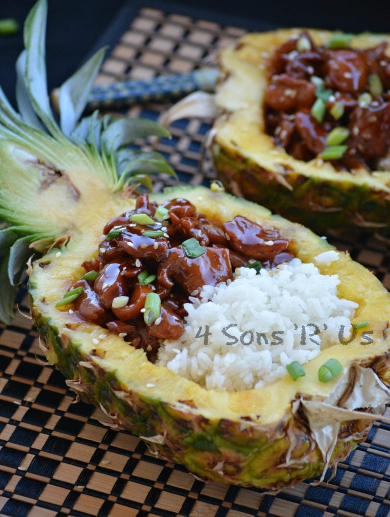 Chicken Teriyaki Pineapple Boats shows saucey, teriyaki glazed chicken pieces served next to tender white rice in a halved, hollowed out pineapple bowl