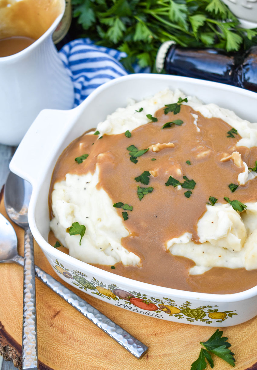 whipped potatoes with dijon stout gravy in a small white baking dish