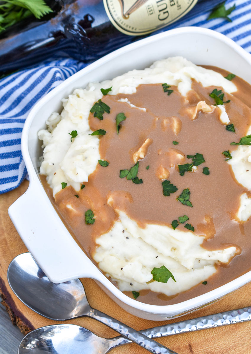 whipped potatoes with dijon stout gravy in a small white baking dish