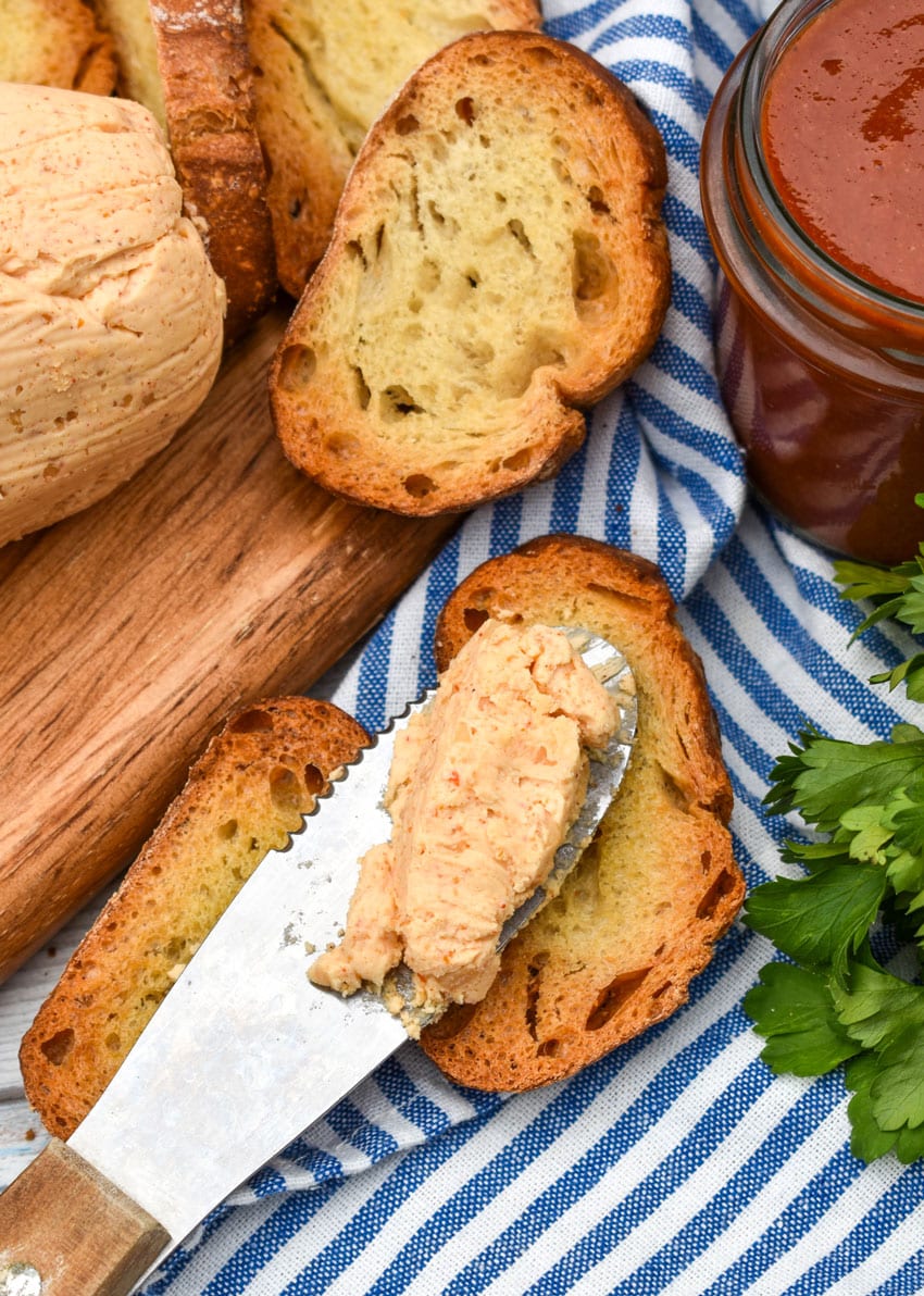 honey sriracha butter on a silver spreader resting on a toasted baguette slice