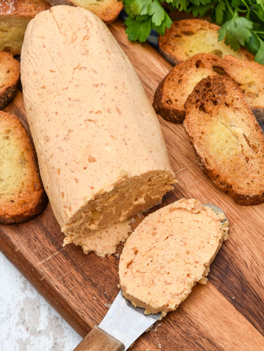 a slice of easy sriracha honey flavored compound butter resting on a wooden cutting board