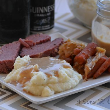 whipped mashed potatoes with Dijon stout gravy on a white plate with slices of corned beef and roasted carrots