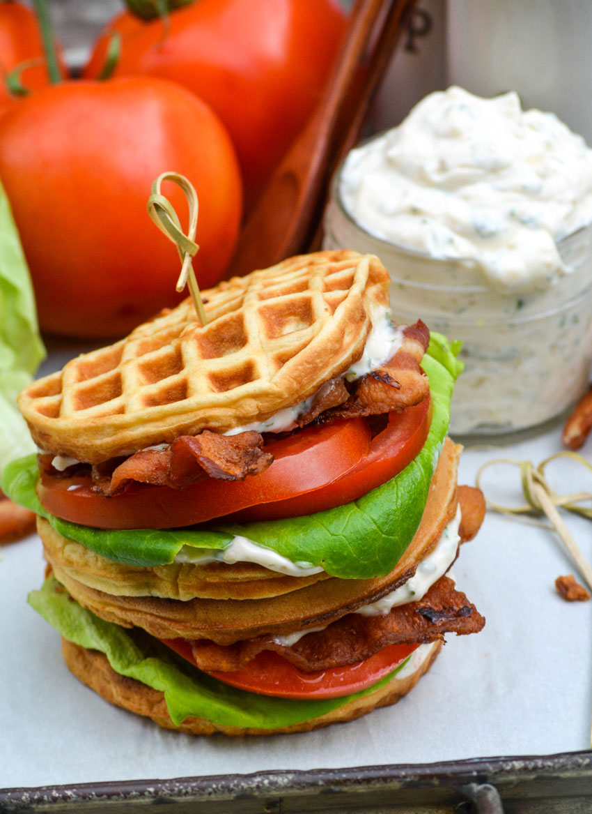 a bacon lettuce and tomato waffle-wich with a toothpick stuck in the middle in front of a jar of herbed mayo