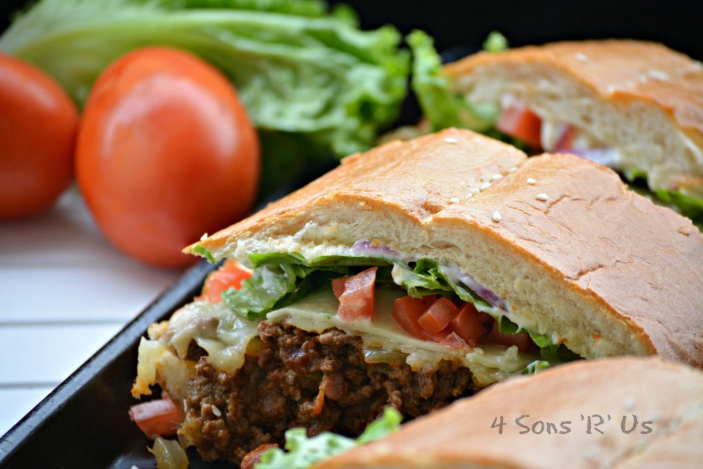 Bacon Cheeseburger Stuffed French Bread sliced into a sandwich serving on a dark baking sheet