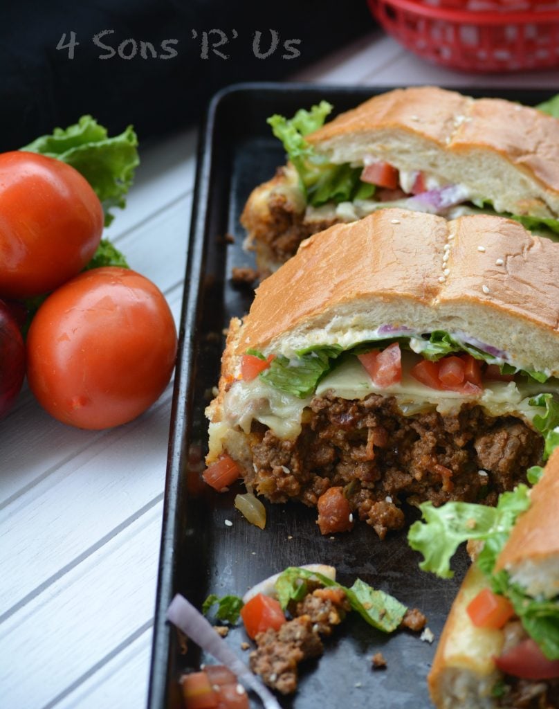 Bacon Cheeseburger Stuffed French Bread shown slice into sandwiches on a dark baking sheet