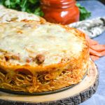 baked spaghetti pie served on a wooden cutting board