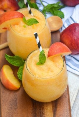 peach white wine slushies in stemless win glasses garnished with fresh sliced of fruit and mint leaves