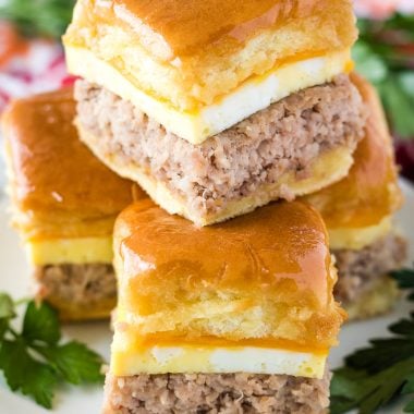 sausage egg and cheese breakfast sliders stacked on a white plate