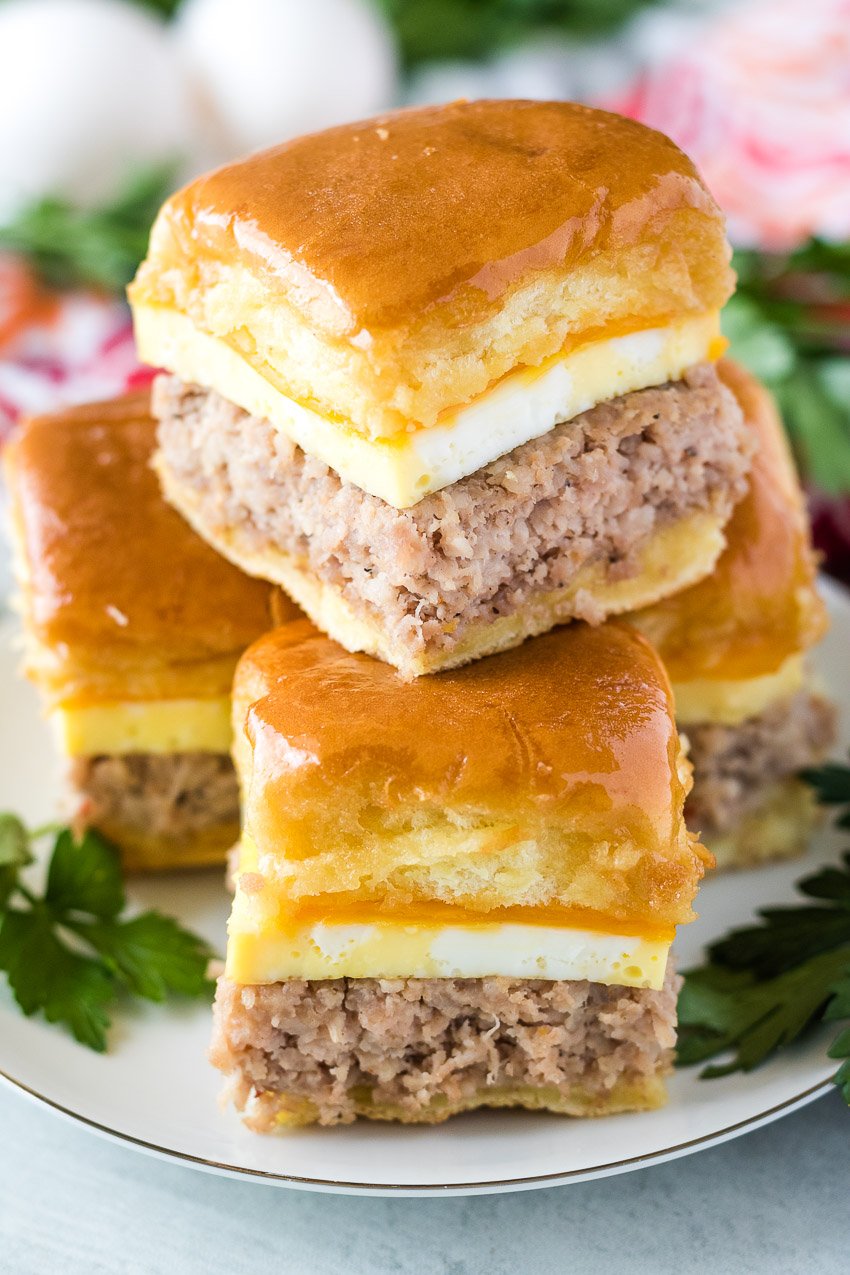 sausage egg and cheese breakfast sliders stacked on a white plate